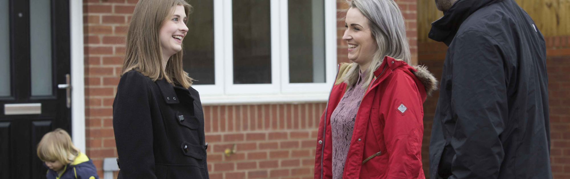 Couple meeting another woman outside a property